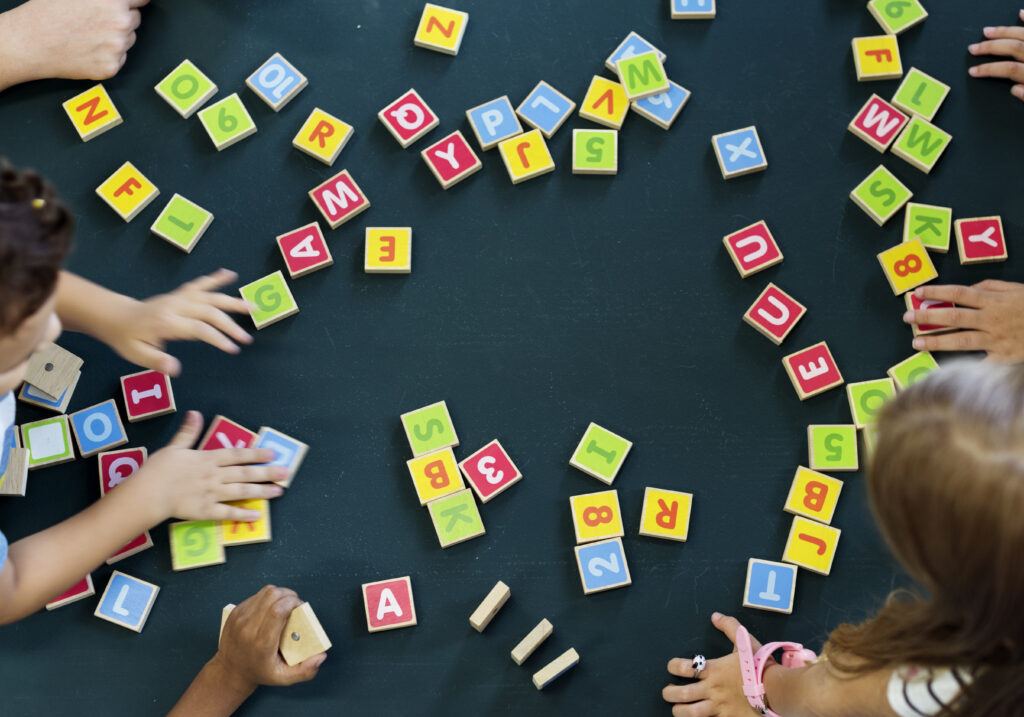 Kindern spielen eine Vokabel Spiel mit bunten Buchstaben Kacheln